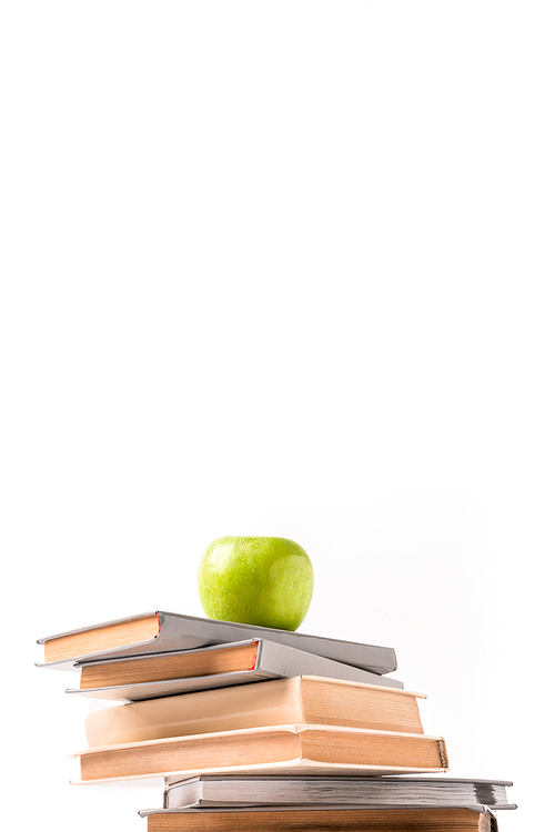 Low angle view of pile of books with apple on top isolated on white