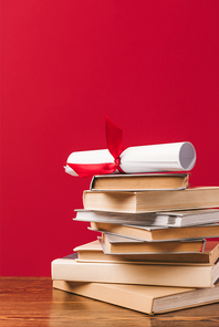 Diploma on top of stack of books on red