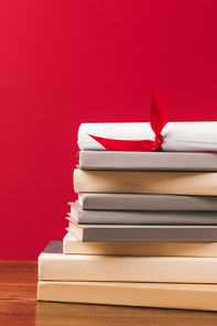 Cropped image of diploma on top of stack of books on red