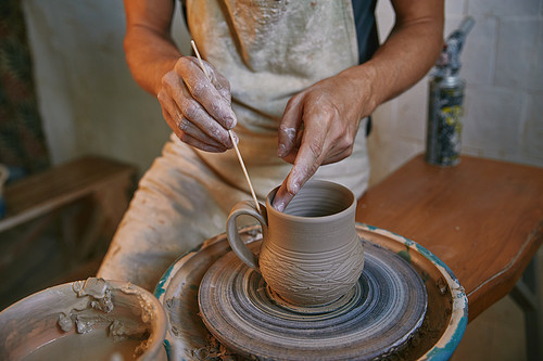 cropped image of man decorating clay pot at workshop