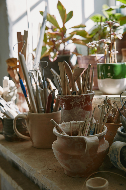 selective focus of pottery tools and paintbrushes at table in pottery studio