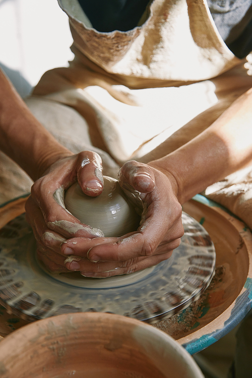 selective focus of professional potter working on pottery wheel at workshop