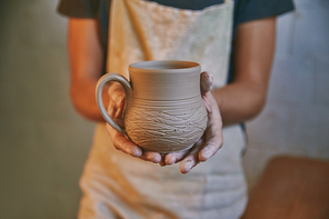 selective focus of man holding clay pot in pottery studio