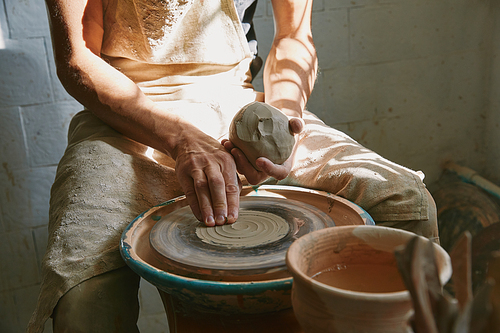 partial view of professional potter working with clay at workshop