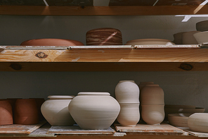 ceramic bowls and dishes on wooden shelves at pottery studio