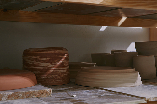 ceramic bowls and dishes on wooden shelves at pottery studio