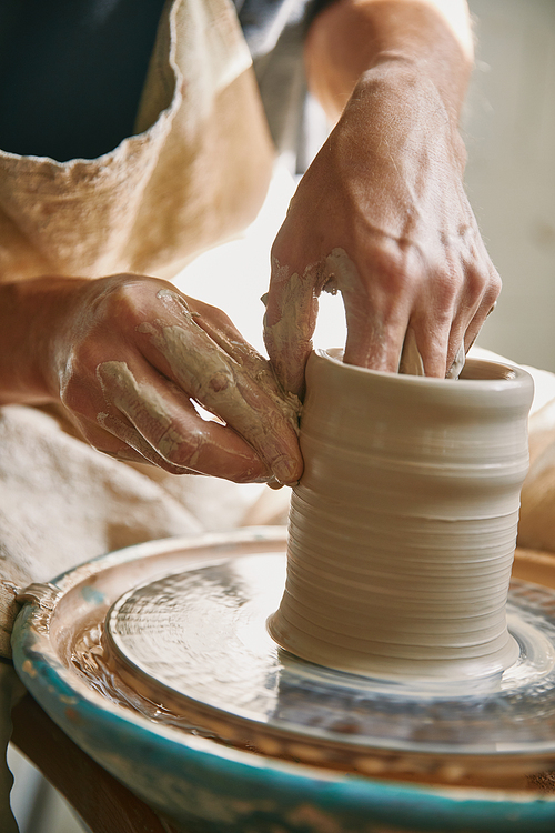 selective focus of man hands working on pottery wheel at workshop