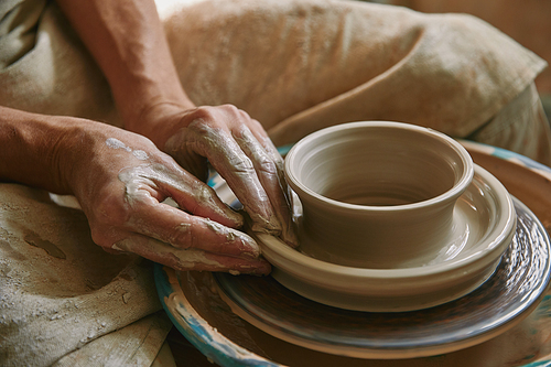 close up view of professional potter working on pottery wheel at workshop