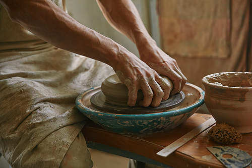 cropped image of male craftsman working on potters wheel at pottery studio