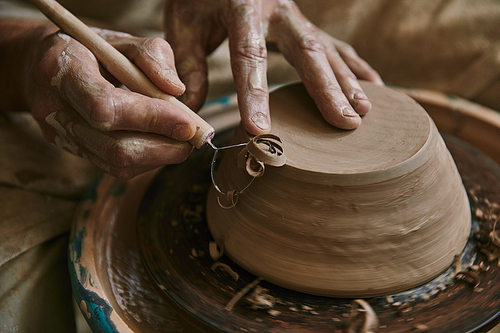 close up view of professional potter decorating clay pot at workshop