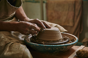 selective focus of professional potter decorating clay pot at workshop