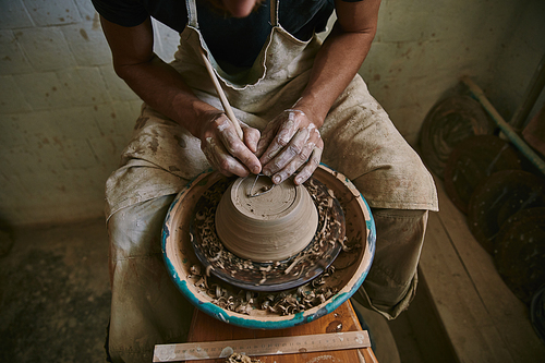 cropped image of professional potter decorating clay pot at workshop