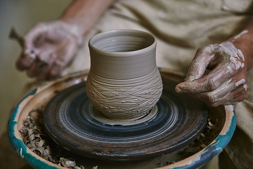 cropped image of male craftsman working on potters wheel at workshop