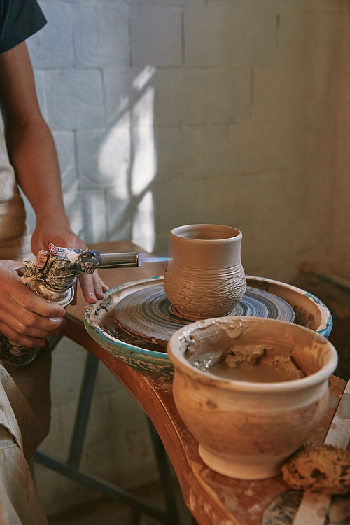 partial view of male potter in apron firing clay pot at pottery studio