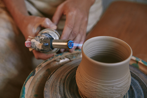 selective focus of male potter firing clay pot at pottery studio