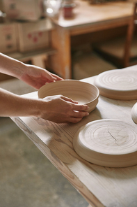 cropped image of woman putting ceramic dish on table at workshop