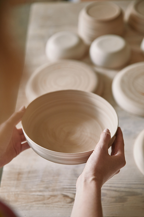 selective focus of woman holding ceramic dish at pottery studio