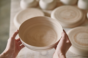 cropped image of woman holding ceramic dish at pottery studio