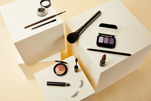 high angle view of various makeup accessories on beige cubes