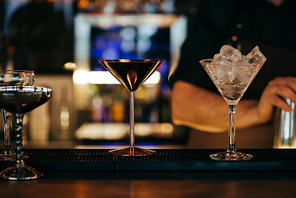 selective focus of alcoholic cocktails on counter with barman on background