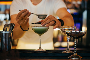 selective focus of bartender preparing alcoholic cocktail using sieve