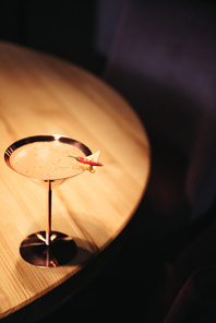 alcoholic cocktail in metal glass decorated with chili pepper and nacho chip on wooden table