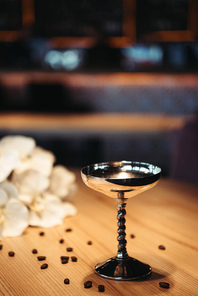 alcoholic cocktail in metal glass decorated with coffee beans on wooden table with dark background