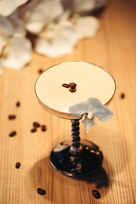 alcoholic cocktail in metal glass decorated with orchid flower and coffee beans on wooden table