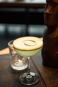 selective focus of delicious alcoholic cocktail with foam on wooden table in bar