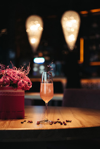 selective focus of pink alcoholic cocktail with flowers on dark background