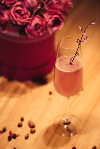 selective focus of pink alcoholic cocktail decorated with dry flowers on wooden background