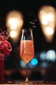 selective focus of pink alcoholic cocktail decorated with dry flowers on dark background