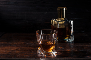 cognac in glass and bottle of luxury alcohol on dark wooden table