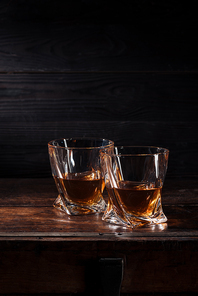 two glasses of whiskey on brown wooden table