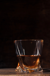 close-up view of whiskey in glass on wooden table on black