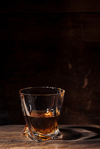 close-up view of whiskey in glass and reflection on wooden table