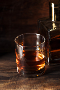 close-up view of glass of bourbon and bottle on wooden table