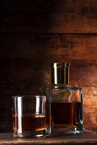 close-up view of glass of brandy and bottle on wooden table