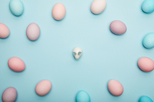 Top view of easter eggs and toy bunny on blue background