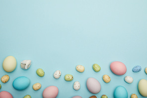 Top view of toy bunny, easter chicken and quail eggs on blue background with cope space