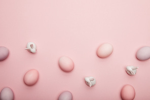 Top view of toy bunnies and easter eggs on pink background