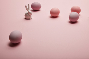 toy bunny and painted easter eggs on pink background
