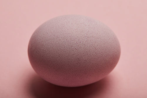 Close up of painted easter egg on pink background