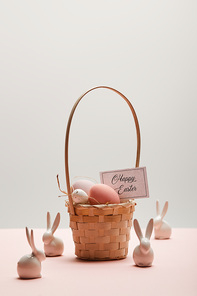 easter chicken and quail egg in straw basket, card with happy easter lettering and toy rabbits