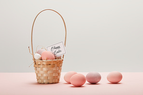 easter chicken and quail egg in straw basket, card with happy easter lettering on grey background