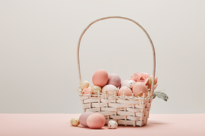 eater chicken and quail eggs in straw basket with flower on grey background