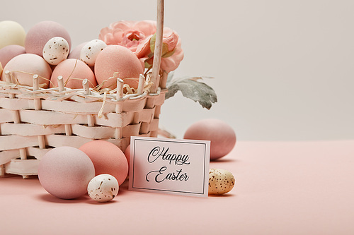 easter chicken and quail eggs in straw basket with flower and card with happy easter lettering