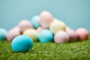 selective focus of easter eggs on grass on blue background