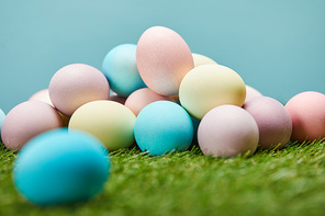 selective focus of painted easter eggs on grass and on blue background