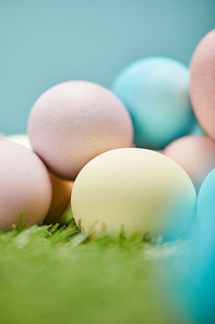 close up of painted easter eggs on grass and on blue background